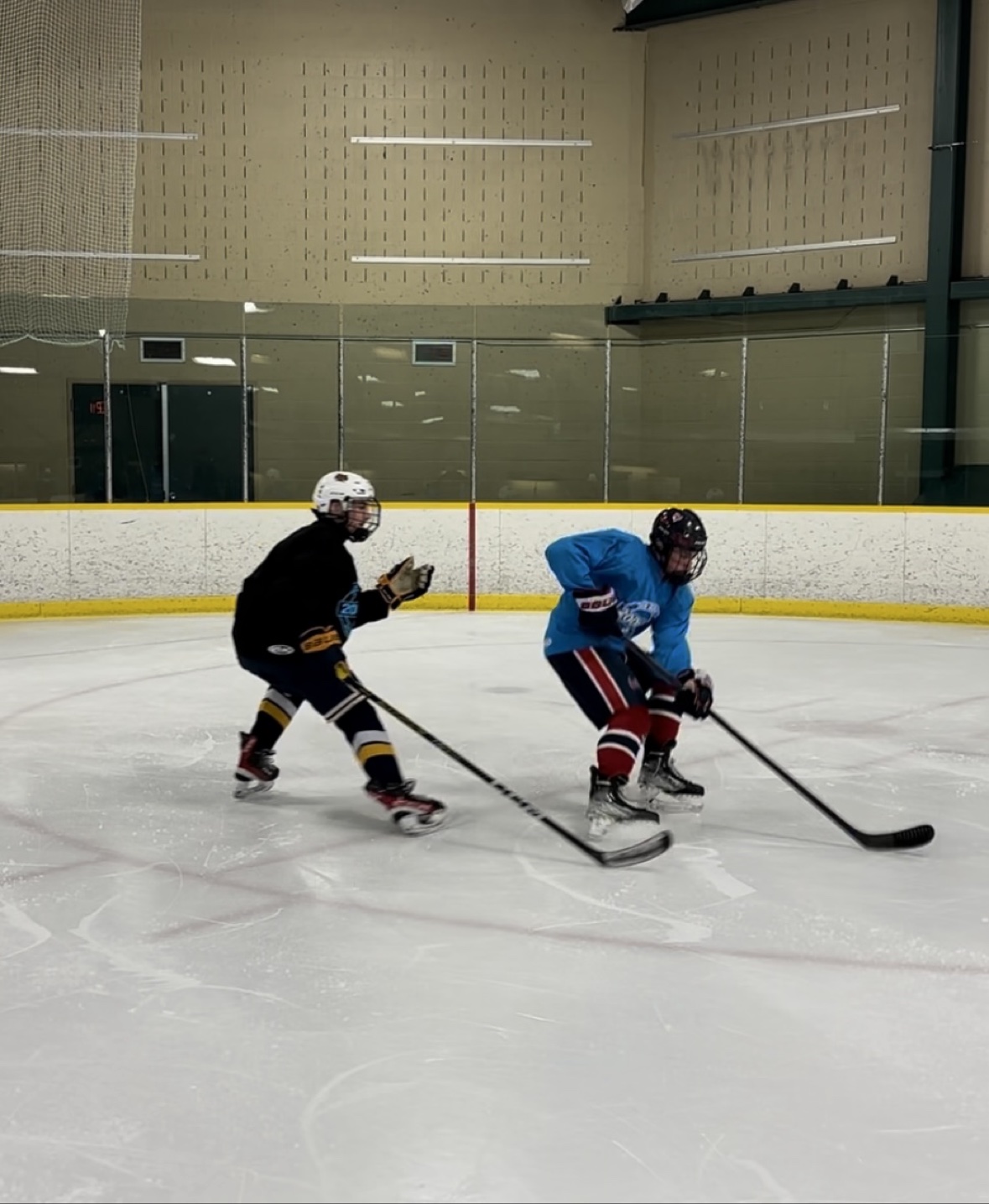 Two players competing for the puck during an on-ice drill