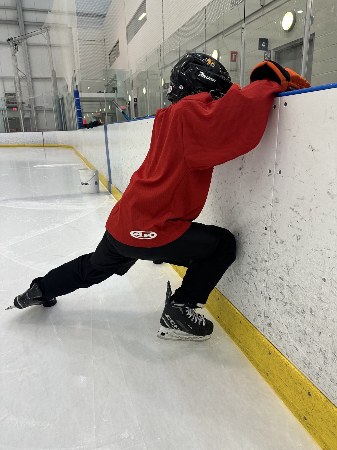 Hockey player working on mobility at the rink boards
