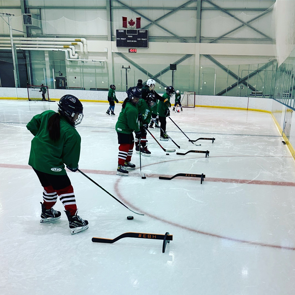 A line of hockey players completing a puck-control exercise on the ice