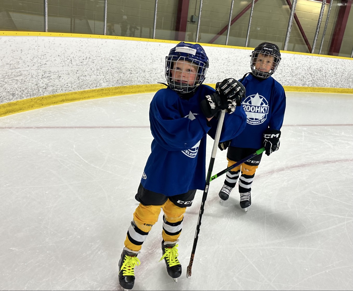 Two young hockey players standing together on the ice